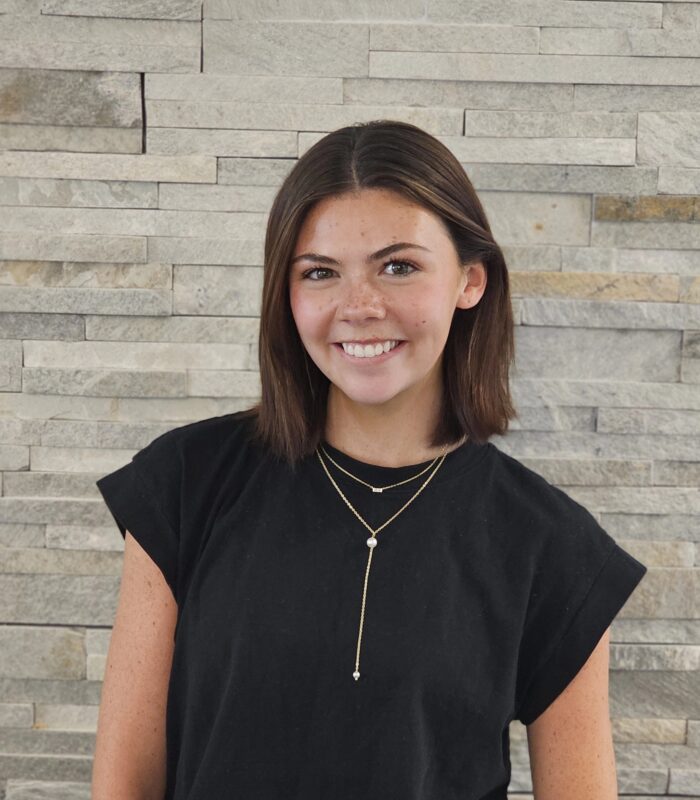 Meet Our Team - Professional and Welcoming Group at a Conference Table Faces the Camera, Team Leader Sitting on the Table with Arms Folded